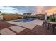 Backyard pool featuring a waterfall, seating, and outdoor dining area at dusk at 9547 W Chama Dr, Peoria, AZ 85383