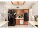 Well-lit kitchen features wood cabinets, black refrigerator, and neutral tile flooring at 956 N 58Th St, Mesa, AZ 85205