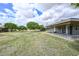 A home's backyard features a well-maintained lawn, mature trees, and a covered patio area at 10317 W Desert Forest Cir, Sun City, AZ 85351