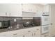 Close up of kitchen with white cabinets, granite counters and modern appliances at 10317 W Desert Forest Cir, Sun City, AZ 85351
