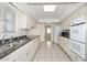 Bright kitchen featuring white cabinetry, tile flooring, and stainless double basin sink at 10317 W Desert Forest Cir, Sun City, AZ 85351