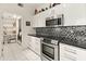 Modern kitchen featuring white cabinets, stainless steel appliances, and stylish black and white backsplash at 11333 N 92Nd St # 1021, Scottsdale, AZ 85260