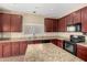 Gourmet kitchen featuring granite countertops, cherry wood cabinets, and modern appliances at 17358 N 185Th Ln, Surprise, AZ 85374