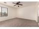 A bedroom featuring neutral carpet, a ceiling fan, and a large window at 18856 N Comet Trl, Maricopa, AZ 85138