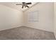 A spacious bedroom with neutral carpet, ceiling fan, and a large window at 18856 N Comet Trl, Maricopa, AZ 85138