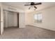 A spacious bedroom with neutral carpet, ceiling fan, closet and a large window at 18856 N Comet Trl, Maricopa, AZ 85138