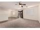 Spacious living room featuring a ceiling fan, neutral carpet, and tile flooring at 18856 N Comet Trl, Maricopa, AZ 85138