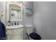 Charming powder room with white vanity, decorative mirror, and beach-themed artwork at 1954 E Vista Dr, Phoenix, AZ 85022