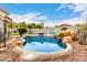 Inviting pool area featuring a waterfall, desert landscaping, and charming blue chairs at 1954 E Vista Dr, Phoenix, AZ 85022