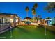 Inviting backyard with putting green, pool, hot tub, and outdoor seating area surrounded by mature palms at 20497 E Appaloosa Dr, Queen Creek, AZ 85142