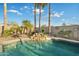 Relaxing pool area featuring a rock waterfall, palm trees, and ample space for outdoor enjoyment at 20497 E Appaloosa Dr, Queen Creek, AZ 85142