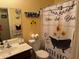 Bathroom with decorative shower curtain, toilet, sink, mirror, and yellow accents at 25798 W Miami St, Buckeye, AZ 85326