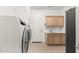 Tiled laundry room equipped with modern washer and dryer, storage cabinets, sink, and dark refrigerator at 27204 N 86Th Dr, Peoria, AZ 85383