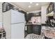 Kitchen with black cabinets, white appliances, and a pass-through to the living room at 3002 N 32Nd St # 13, Phoenix, AZ 85018
