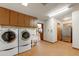 Spacious laundry area has cabinetry and stainless-steel refrigerator, with laundry sink and modern washer and dryer set at 3264 E Vineyard Rd, Phoenix, AZ 85042
