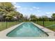 Beautiful in-ground pool surrounded by lush greenery and a secure fence, perfect for relaxation at 3264 E Vineyard Rd, Phoenix, AZ 85042