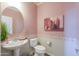 Powder room featuring a pedestal sink, round mirror, and stylish decor accents at 40262 W Molly Ln # 138, Maricopa, AZ 85138
