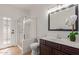 Bright bathroom with glass-enclosed shower, wood vanity and a decorative mirror at 5332 W Linda Ln, Chandler, AZ 85226