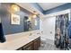 Stylish bathroom with elegant lighting, blue walls, a shower-tub combo and tropical decor at 6257 E Catalina Dr, Scottsdale, AZ 85251