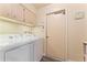 Clean laundry room with washer, dryer, overhead cabinets, and access door at 6257 E Catalina Dr, Scottsdale, AZ 85251