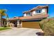 Two-story home featuring a charming front porch, two-car garage, tile roof, and low-maintenance desert landscaping at 650 E Daniella E Dr, San Tan Valley, AZ 85140