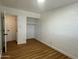 This bedroom features an open closet space, wood floors, and white painted brick walls at 7129 W Meadowbrook Ave, Phoenix, AZ 85033