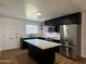 Well-lit kitchen features black cabinets, stainless steel appliances, island with quartz countertop, and updated backsplash at 7129 W Meadowbrook Ave, Phoenix, AZ 85033