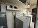 Functional laundry room features a washer, dryer, water heater, and storage shelves at 7129 W Meadowbrook Ave, Phoenix, AZ 85033