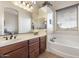 Bathroom featuring double sinks, a soaking tub, and natural light from a window at 8359 E Ingram Cir, Mesa, AZ 85207