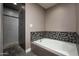 Modern bathroom featuring a soaking tub with mosaic tile surround and a walk-in shower with gray tile at 8369 E Del Camino Dr, Scottsdale, AZ 85258