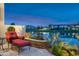 Relaxing patio with red chaise lounge overlooking a peaceful lake and beautiful building complex at 8369 E Del Camino Dr, Scottsdale, AZ 85258