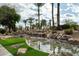 Scenic water feature showcasing rocks, palm trees, flowers, and a tranquil stream in the community at 8369 E Del Camino Dr, Scottsdale, AZ 85258