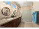 Well lit primary bathroom featuring double sinks with granite counters, a glass enclosed shower, and tan tile flooring at 15560 W Clear Canyon Dr, Surprise, AZ 85374