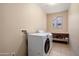 Well-lit laundry room with a front-loading washer, dryer, built-in counter, and tile flooring at 15560 W Clear Canyon Dr, Surprise, AZ 85374