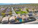 An elevated shot of a quiet neighborhood street with residences near grassy park spaces, desert trees, and distant mountains at 1563 S 227Th Ave, Buckeye, AZ 85326