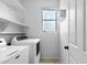 Functional laundry room with modern washer and dryer, window offering natural light and shelving for storage at 16653 N 169Th Ave, Surprise, AZ 85388