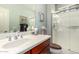 Bright bathroom with a cherry vanity, shower, and a decorative mirror at 1775 N 164Th Dr, Goodyear, AZ 85395
