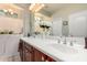 Bright bathroom featuring a dual sink vanity with a large mirror and a decorative floral arrangement at 1775 N 164Th Dr, Goodyear, AZ 85395