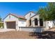 This single-story home has a desert landscape, two-car garage, and inviting porch with a seating area at 1775 N 164Th Dr, Goodyear, AZ 85395