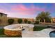 Inviting backyard with a fire pit area surrounded by stone seating, desert landscaping, and lush grass at 2333 N 87Th Pl, Mesa, AZ 85207