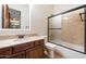 Bathroom featuring a shower-tub combo with glass doors and a stone countertop vanity at 2333 N 87Th Pl, Mesa, AZ 85207
