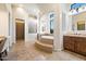 Elegant bathroom featuring a soaking tub, walk-in shower, and dual vanities, all with neutral tile and natural light at 2333 N 87Th Pl, Mesa, AZ 85207