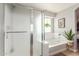 Bathroom showcasing a glass-enclosed shower, soaking tub, large window, and tile flooring at 24805 W Vista Norte St, Buckeye, AZ 85326