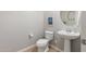 Powder room with white toilet, pedestal sink, stylish mirror, and neutral wall color at 24805 W Vista Norte St, Buckeye, AZ 85326