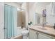 Well-lit bathroom featuring a shower-tub combo with a blue curtain, a vanity with a sink, and modern fixtures at 26336 W Tina Ln, Buckeye, AZ 85396
