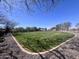 A large green lawn at the dog park, bordered with desert landscaping and sheltered benches and gazebos at 26336 W Tina Ln, Buckeye, AZ 85396