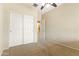 This bedroom features neutral carpeting, a ceiling fan, and a closet with sliding doors at 3253 N 138Th Ave, Avondale, AZ 85392