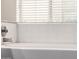 Close up of the tiled tub and shower featuring a window with blinds for privacy at 3348 E Sequoia Dr, Phoenix, AZ 85050