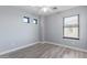 A cozy gray bedroom features modern square windows, natural light, and laminate flooring at 41581 W Somerset Dr, Maricopa, AZ 85138