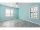 A bright bedroom featuring blue walls, shuttered windows, and stylish laminate flooring at 41581 W Somerset Dr, Maricopa, AZ 85138